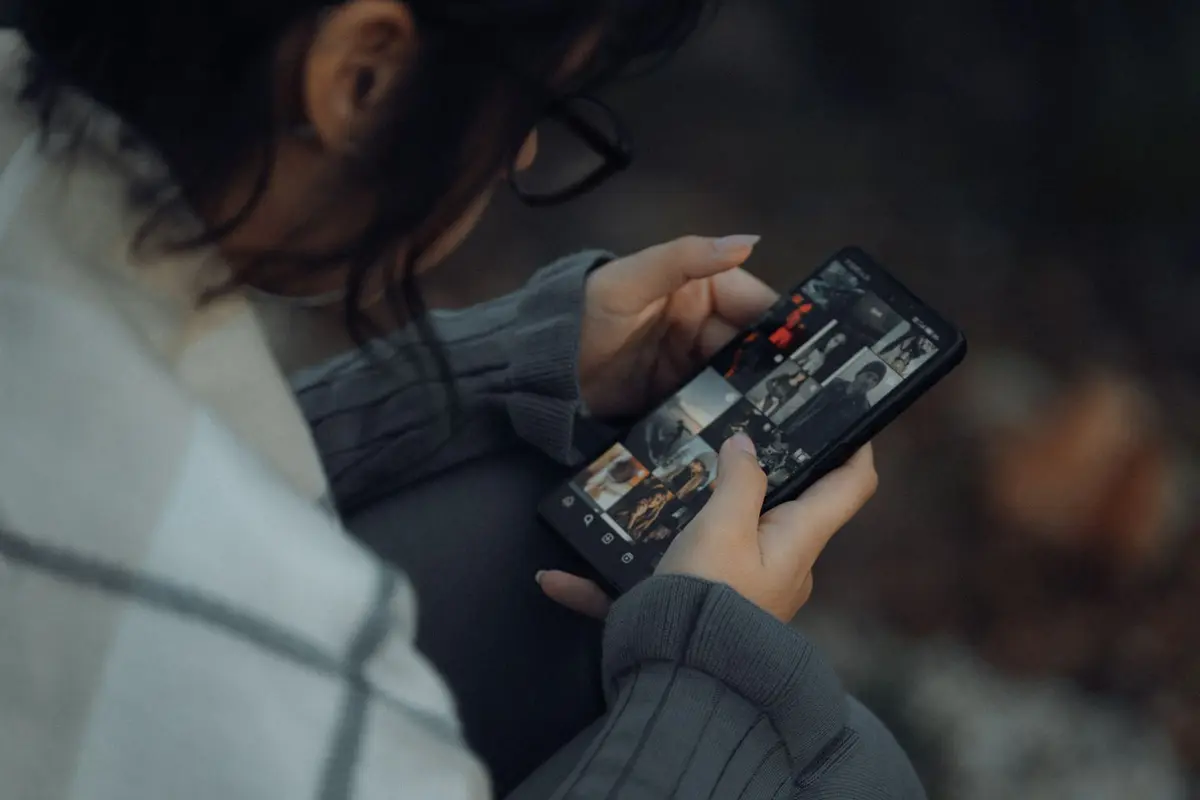 Over the shoulder view of a woman browsing a photo gallery on her smartphone outdoors
